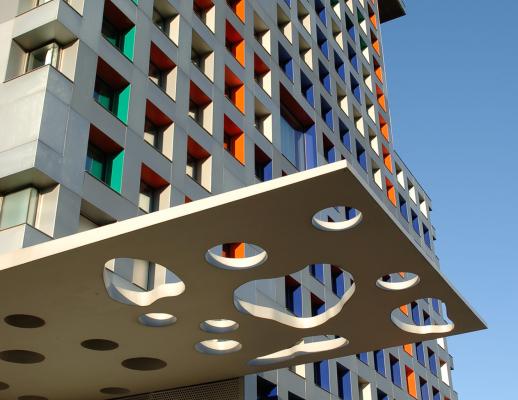 Partial image of Simmons Hall entrance with many windows covering the building, blue sky in the background.